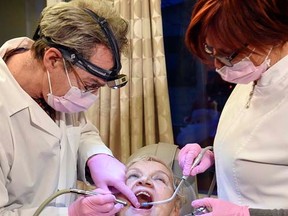 Dr. Christian Caron and dental assistant Suzie Bernard treats a patient, Friday, January 23, 2015. SIMON CLARK / QMI AGENCY