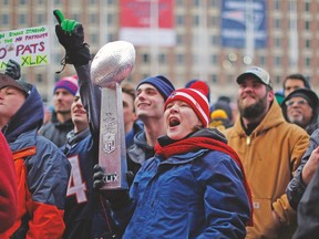 A Patriots fan, holding a model of the Vince Lombardi trophy, cheers during a send-off rally for the team yesterday in Boston. (REUTERS)