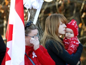 A woman wipes a tear away as a mother holds her child as members of the RCMP and members of other police departments walk in the funeral procession for RCMP Const.. David Wynn in St. Albert on Monday. (IAN KUCERAK/Edmonton Sun)