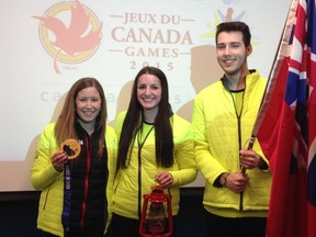 Kaitlyn Lawes (left) shows off her Olympic gold medal Tuesday as she poses with Canada Games lantern-bearer Christian Highem and flag-bearer Kennan Brown.