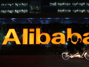 People ride a double bicycle past a logo of The Alibaba Group at the company's headquarters on the outskirts of Hangzhou, Zhejiang province in this file photo taken Nov. 10, 2014.  REUTERS/Aly Song/Files