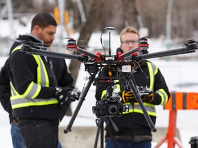 Co-owners E.J. Burrows (left), Connor Burns, and pilot Andrew Pohlmann (back) with Skymatics fly a drone outside of the Kinsmen Sports Centre in Edmonton, Alta., on Wednesday, Jan. 28, 2015. The drone will be used today to film the Walterdale Bridge construction and the Rogers Place arena construction. The flight is downtown Edmonton first drone flight. Ian Kucerak/Edmonton Sun/ QMI Agency