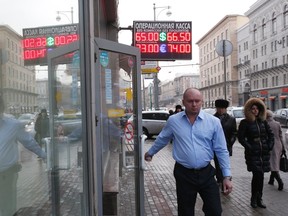 People walk past a board showing currency exchange rates in Moscow, January 26, 2015. The Russian rouble fell sharply on opening on Monday, following a weekend of violence in eastern Ukraine and threats of further Western sanctions against Russia. (REUTERS/Maxim Zmeyev)
