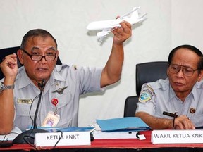 Tatang Kurniadi (L), chief of the National Transportation Safety Committee (NTSC) holds a model plane during a news conference in Jakarta January 29, 2015.
   REUTERS/Darren Whiteside
