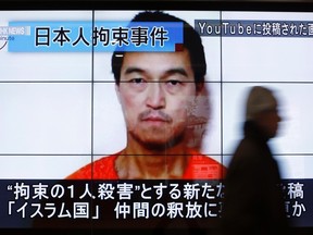 A man walks past screens displaying a television news program showing an image of Kenji Goto, one of two Japanese citizens taken captive by Islamic State militants, on a street in Tokyo January 25, 2015. The words on the screen read "Japanese hostage incident" (top L) and "a still image posted on YouTube" (top R).    (REUTERS/Yuya Shino)
