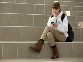 Michaela Molloy, 16, a student at St. Andre Bessette Catholic high school in London, uses the schools Wi-Fi while sitting on a massive staircase, a gathering area in the school. (Mike Hensen, The London Free Press)