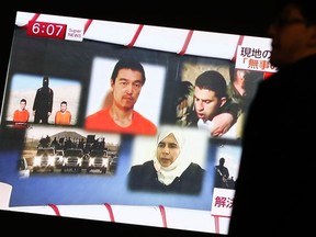 A man walks past a TV screen broadcasting a news program about Islamic State hostages Jordanian air force pilot Muath al-Kasaesbeh (top R) and Japanese journalist Kenji Goto (top C), along a street in Tokyo on Jan. 29, 2015. An audio message purportedly from Goto being held by Islamic State militants said al-Kasaesbeh also captured by the group would be killed unless Sajida al-Rishawi (bottom R), an Iraqi female prisoner in Jordan, was released by sunset on Thursday. (REUTERS/Yuya Shino)