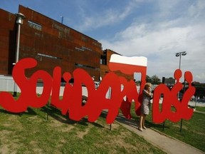 A woman stands next to a Solidarity logo in front of the newly open European Solidarity Centre during the 34th anniversary of emerging Solidarity trade union at the historic shipyard area in Gdansk, northern Poland in this August 31, 2014 file photograph. Reuters/Kacper Pempel/Files