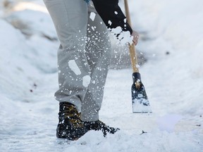 City of Edmonton Municipal Enforcement Officer Brendan Bolstad uses an ice scraper to determine the depth of snow and ice while inspecting sidewalks for snow removal in south Edmonton, Alta., on Thursday, Jan. 22, 2015. (Ian Kucerak/Edmonton Sun/ QMI Agency)