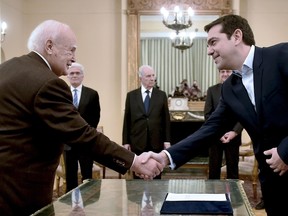 Syriza's leader Alexis Tsipras (R) shakes hands with Greece's President Karolos Papoulias (L) as he is sworn in as Greek Prime Minister at the Presidential Palace in Athens on January 26, 2015. Tsipras' party took more than 36 percent of the vote in Sunday's general election, becoming the first elected movement in Europe openly opposed to austerity.  (AFP photo)
