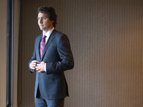 Liberal leader Justin Trudeau buttons up his suit jacket while looking out a window at the Hilton Hotel, where the Liberal caucus was holding their winter strategy meeting, in London, Ont., on January. 20, 2015. (CRAIG GLOVER/QMI Agency)