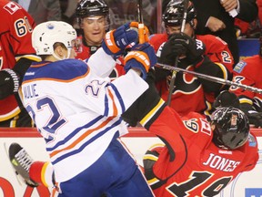 Calgary Flames David Jones is hammered by Edmonton Oilers Keith Aulie in NHL hockey action at the Scotiabank Saddledome in Calgary, Alta. on Wednesday December 31, 2014. Mike Drew/Calgary Sun/QMI Agency