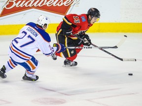 Dec 31, 2014; Calgary, Alberta, CAN; Calgary Flames left wing Johnny Gaudreau (13) controls the puck as Edmonton Oilers center Boyd Gordon (27) defends during the second period at Scotiabank Saddledome. Mandatory Credit: Sergei Belski-USA TODAY Sports