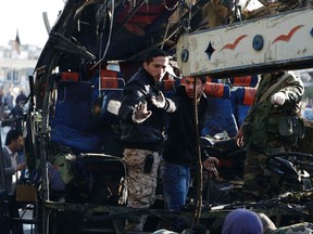 Members of Syrian security services and soldiers gesture as they stand on the wreckage of a bus on which an explosion occurred, in central Damascus February 1, 2015. The explosion tore apart the bus thought to be carrying Lebanese Shi'ite Muslim pilgrims in Damascus on Sunday, killing at least six people, a Reuters witness and local media said.  REUTERS/Omar Sanadiki