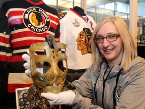 Debbie Schween, gallery director of the Manitoba Sports Hall of Fame, displays Terry Sawchuk"s goalie mask next to the jerseys of Billy Mosienko and Jonathan Toews in Winnipeg, Man. Thursday January 29, 2015. (Brian Donogh/Winnipeg Sun/QMI Agency)