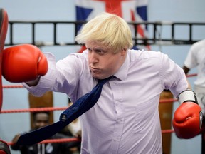 London Mayor Boris Johnson boxes with a trainer during a visit to Fight for Peace Academy in North Woolwich, London, on October 28, 2014. Fight for Peace is dedicated to helping at-risk youth find success in life. (AFP PHOTO)