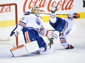 Edmonton Oilers Ryan Nugent-Hopkins, right, falls after catching his stick on goaltender Ben Scrivens' neck against the Calgary Flames at the Scotiabank Saddledome on Saturday January 31, 2015 in Calgary, Alta. Carys Richards/Special to the Calgary Sun/QMI Agency