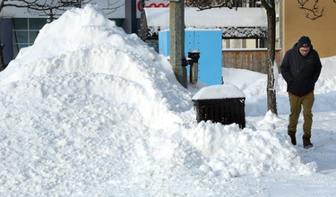 A pedestrian passes a large pile of snow on York Street in London, Ont., after a snowplow had passed on February 2, 2015. (MORRIS LAMONT/QMI Agency)