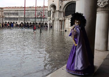 A masked reveller poses along the flooded St. Mark's Square during a period of seasonal high water and on the first day of carnival, in Venice February 1, 2015. REUTERS/Stefano Rellandini