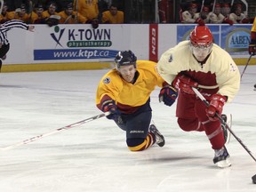 Queen's Golden Gaels defenceman Patrick McEachen dives for the puck against Royal Military College Paladins’ Kyle Phillips during the 2014 Carr-Harris Cup game at the Rogers K-Rock Centre. (Julia McKay/The Whig-Standard)