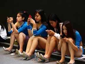 Promotional models use their smartphones during their break at the Global Mobile Internet Conference in Beijing May 6, 2014. REUTERS/Kim Kyung-Hoon