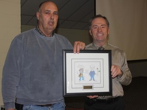 Lambton Soil and Crop Improvement Association (LSCIA) director Dave Williams, left, presents OMAFRA cereal crop specialist Peter Johnson with a framed cartoon in recognition of his many years of service and contribution to the LSCIA. Johnson is retiring from OMAFRA in January after a career that spanned more than 30 years.