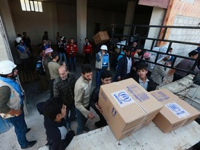 People unpack humanitarian aid from trucks in Duma, Damascus March 29, 2014. A delegation from the U.N., the World Food Program, UNICEF and the WHO, accompanied by the Syrian Red Crescent, visited for the second time the eastern Damascus suburb of Ghouta, carrying humanitarian aid to be distributed to the residents and moved in the area accompanied by the Free Syrian Army, activists said. (REUTERS/Bassam Khabieh)