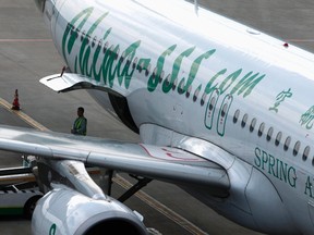An employee of Spring Airlines stands next to an Airbus A320 aircraft at Hongqiao airport in Shanghai July 6, 2012. REUTERS/Aly Song