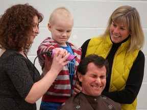 Truedell Public School teacher Kent Rich gets the first ceremonial head shave from Ayden Barber-Reid as parent-volunteer Pam Lynch, left, and Grade one teacher Cheryl Dempster help during a head shaving event at the school. (Ian MacAlpine/The Whig-Standard)