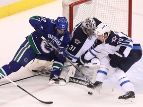 Winnipeg Jets ' goalie Ondrej Pavelec (centre) stops a shot as Winnipeg Jets ' Tobias Enstrom (right) defends against Vancouver Canucks’ Daniel Sedin (left) during the first period of NHL game at Rogers Arena in Vancouver, B.C. on Tuesday February 3, 2015. Carmine Marinelli/QMI Agency