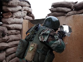 A Kurdish Peshmerga fighter aims his weapon through a hole in a wall on the front line of fighting against Islamic State militants in the outskirts of Mosul January 30, 2015.  (REUTERS/Ari Jalal)