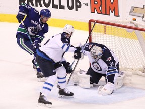 Winnipeg Jets goalie Ondrej Pavelec (right) blocks a shot  from Vancouver Canucks’ Alex Burrows (left) as Winnipeg Jet Mark Stuart (centre) defends during the second period of NHL game at Rogers Arena in Vancouver, B.C. on Tuesday February 3, 2015.