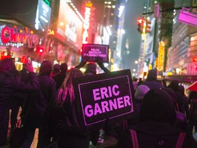 Protesters, demanding justice for Eric Garner, hold placards while marching through Times Square, New York December 5, 2014.  REUTERS/Adrees Lati