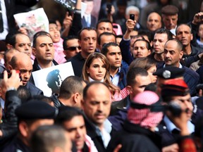 Jordan's Queen Rania (C) holds a picture of recently executed Jordanian pilot Muath al-Kasasbeh, with the words in Arabic reading "Muath is a martyr of right", during a march after Friday prayers in downtown Amman February 6, 2015. Thousands of Jordanians gathered to show their loyalty to the King and to show solidarity with the family of the pilot, Muath al-Kasasbeh, killed by Islamic State. REUTERS/Muhammad Hamed