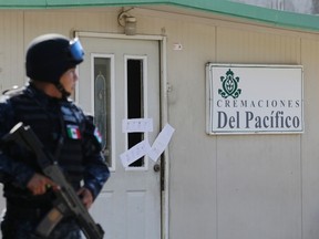A police officer stands guard outside the sealed-off building housing a crematorium in Llano Largo, on the outskirts of Acapulco, February 6, 2015. Sixty-one bodies were discovered in an abandoned crematorium near the decaying seaside resort of Acapulco in Western Mexico, local authorities said on Friday, adding they believed it was a case of negligence rather than linked to drug violence. The bodies, clothed, wrapped in sheets and sprinkled with lime, were mostly in a state of decomposition. They were found 130 miles (211 km) from the town of Iguala, where 43 student teachers were abducted by corrupt police and apparently massacred by drug gang members. REUTERS/Henry Romero