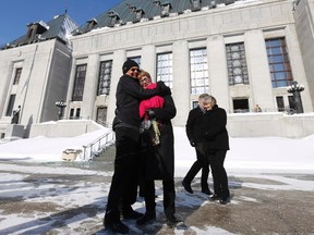 Lee Carter (2nd L) gets a hug from her husband Hollis Johnson outside the Supreme Court of Canada in Ottawa February 6, 2015. The Supreme Court of Canada overturned a ban on physician-assisted suicide on Friday, unanimously reversing a decision it made in 1993 and putting Canada in the company of a handful of Western countries where the practice will be legal. Carter's mother, Kay Carter, traveled to Switzerland to end her life in 2010. REUTERS/Chris Wattie