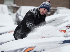 Ryan Marrett brushes off the snow from the cars on the Hyundai lot in Mississauga  on Sunday. (CRAIG ROBERTSON, Toronto Sun)