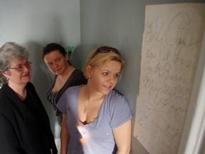 Kay LaRose, left, Agnieszka Cukroswski, middle, and Kinga Kaminski admire a handwritten message they uncovered written on a wall in one of the Elmhurst Inn's dining rooms. HEATHER RIVERS/WOODSTOCK SENTINEL-REVIEW