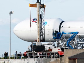 SpaceX workers examine the unmanned Falcon 9 rocket carrying the National Oceanic and Atmospheric Administration's Deep Space Climate Observatory Satellite as it lays horizontally on launch complex 40 at the Cape Canaveral Air Force Station in Cape Canaveral, Fla., Feb. 9, 2015. (SCOTT AUDETTE/Reuters)