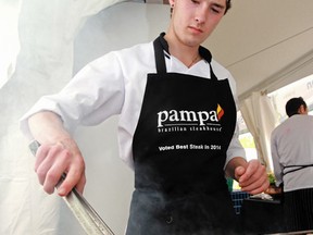 Kiefer (no last name given) watches over the bacon wrapped chicken thighs at the Pampa Brazilian Steakhouse booth, during the Taste of Edmonton in Sir Winston Churchill Square, in downtown Edmonton Alta., on Friday July 18, 2014. David Bloom/Edmonton Sun/ QMI Agency