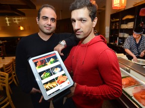 Arash Tajalli-Yazdi, left, and Javad Nazari show the electronic menu they designed to work on a tablet at the Wonder Sushi restaurant in London on Monday February 9, 2015. (MORRIS LAMONT, The London Free Press)