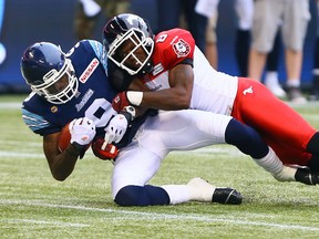 Darvin Adams of the Toronto Argos is taken down by Fred Bennett of the Calgary Stampeders during CFL action at the Rogers Centre in Toronto, Ont. on Saturday July 12, 2014. Dave Abel/Toronto Sun/QMI Agency