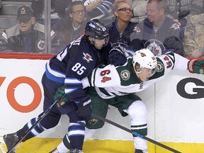 Winnipeg Jets centre Mathieu Perreault (l) checks Minnesota Wild center Mikael Granlund during NHL hockey in Winnipeg, Man. Tuesday, February 10, 2015.
Brian Donogh/Winnipeg Sun/QMI Agency