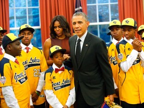 U.S. President Barack Obama (C) winks at departing photographers after he and first lady Michelle Obama (4th L) had their picture taken with members of the Jackie Robinson West All Stars Little League baseball team from Chicago in the Oval Office at the White House in Washington November 6, 2014. (REUTERS)