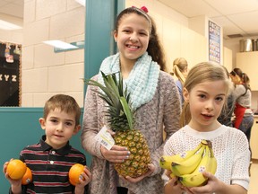 St. Anne school students Declan Harrigan, 6, left, Bianca Iacobelli, 12, and Kaelyn McArthur, 8, pose with some fruit as parent volunteers prepare for the school's morning healthy snack program. The Sarnia school is one of three in Lambton County to join the Student Nutrition Program this month. TYLER KULA/ THE OBSERVER/ QMI AGENCY