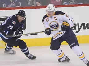 Jets winger Blake Wheeler (left) and Sabres defenceman Tyler Myers chase the puck during NHL action in Winnipeg on Dec. 16, 2014. Myers was traded to the Jets as part of a multiple player trade Wednesday. (Brian Donogh/QMI Agency)
