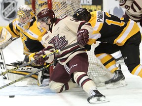 Adam Timleck of the Peterborough Petes, chased by Frontenacs defenceman Jarkko Parikka, brings the puck out in front of Kingston goaltender Lucas Peressini during the first period of an Ontario Hockey League game at the Rogers K-Rock Centre on Wednesday night. (Elliot Ferguson/The Whig-Standard)