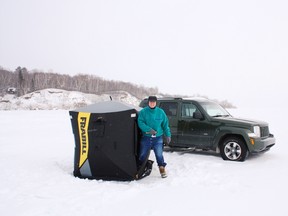Ice angler Emmerson Dober takes shelter from the Lake Wabamun wind