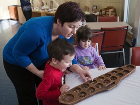 Jen Turner plays Oware with her children Jayden, 3, and Bella, 2, at London Regional Children?s Museum. The ancient game, popular in West Africa and the Caribbean, is part of the museum?s Black History Month display. (DEREK RUTTAN, The London Free Press)