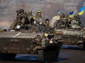 Members of the Ukrainian armed forces ride on armoured personnel carriers (APC) near Debaltseve, eastern Ukraine, February 12, 2015. Germany, France, Russia and Ukraine agreed a deal on Thursday that offers a "glimmer of hope" for an end to fighting in eastern Ukraine after marathon overnight talks.  REUTERS/Gleb Garanich